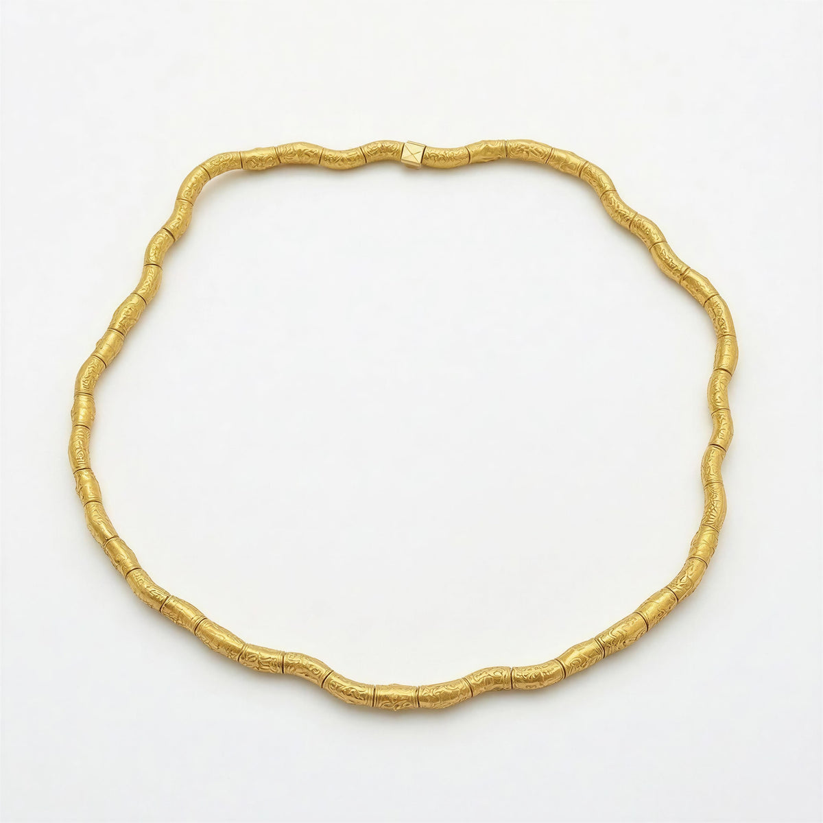 Elegant gold-tone necklace with textured, curved tubular beads forming a continuous loop, showcasing refined craftsmanship in Necklaces - AURELIS.
